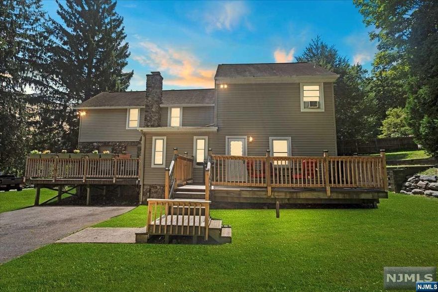 Nestled in a serene, wooded setting, this charming 4-bedroom, 2-bathroom colonial style home beautifully blends rustic charm with modern convenience. The exterior of the home is a striking combination of stone and siding, giving it a warm, inviting appearance. The large wraparound deck, perfect for outdoor entertaining, overlooks a lush and a well-maintained yard. Inside, the home is filled with natural light, especially in the cozy dining area, which is adjacent to a large sliding glass door that opens onto the deck. This space is ideal for casual meals or hosting gatherings. The stone accents continue inside with a stunning fireplace that serves as a focal point, adding to the home's rustic appeal making this home an ideal blend of comfort, style, and functionality.