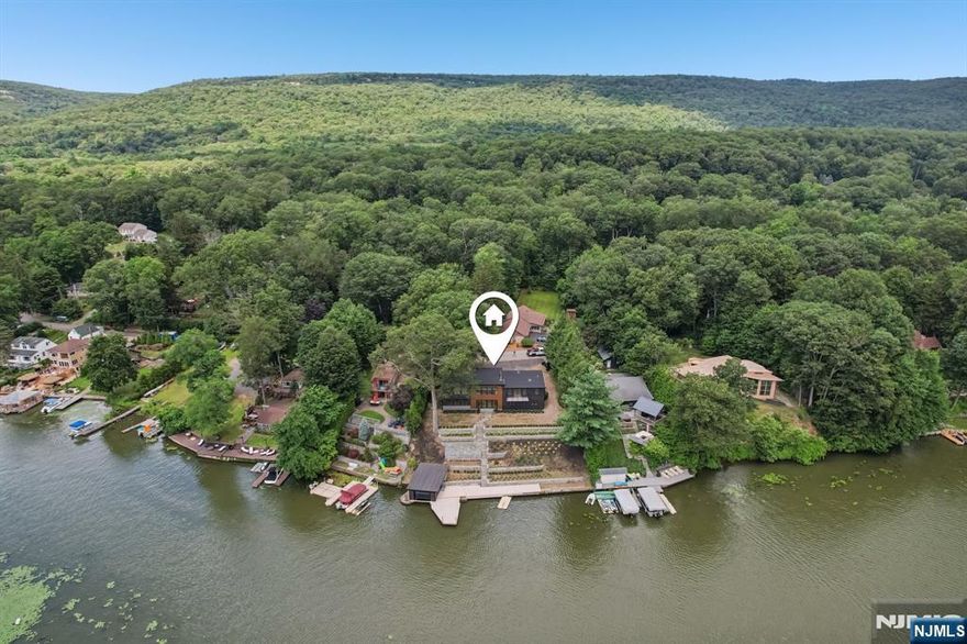 Welcome to an exceptional luxury retreat in sought-after West Milford. This stunning 5-bedroom, 4.5-bath custom home offers the perfect blend of refined elegance, superior craftsmanship, and breathtaking lake views.From the moment you arrive, you'll be captivated by the home's impressive presence and meticulous attention to detail. Inside, a thoughtfully designed open-concept layout showcases soaring ceilings, rich architectural finishes, and an abundance of natural light. The gourmet chef's kitchen is a true showpiece, featuring high-end appliances, custom cabinetry, and an oversized island perfect for both everyday living and entertaining on a grand scale.The expansive living and dining areas flow seamlessly, highlighted by designer touches and panoramic views that bring the outdoors in. A luxurious primary suite offers a private sanctuary, complete with a spa-inspired bath and serene lake vistas. Each additional bedroom is generously sized, with beautifully appointed bathrooms that provide comfort and privacy for family and guests alike.Step outside to experience resort-style living, where stunning outdoor spaces are designed to maximize the picturesque surroundings. Whether hosting gatherings or enjoying quiet mornings overlooking the water, this home delivers an unparalleled lifestyle.Perfectly positioned in a prime location, this one-of-a-kind property combines tranquility, luxury, and convenience making it a rare opportunity you won't want to miss.