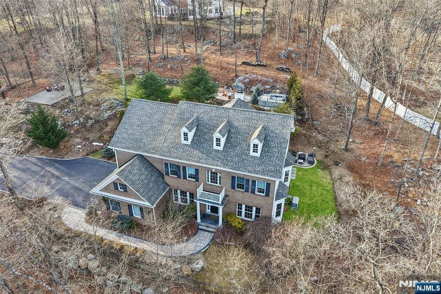 Discover the ultimate luxury retreat in this immaculate Ringwood colonial nestled on 3.2 serene acres. Built in 2004 and meticulously updated, this turn-key residence blends sophisticated architecture with modern comforts. A grand two-story foyer opens to an elegant interior featuring 9'+ ceilings, hardwood floors, and abundant natural light throughout. At the heart of the home is a gourmet eat-in kitchen with recently upgraded granite counters/designer backsplash that flows into a magnificent two-story great room with a fireplace and floor-to-ceiling windows. A formal dining room, living room, home office, and a powder room complete the first level. Upstairs, find 4 bedrooms and 3 full baths, including a primary suite with a tray ceiling, spa-like bath, and walk-in closet. The expansive walk-out basement features high ceilings, a gym, ample space for recreation and everyday living, and an updated powder room. Peace of mind is guaranteed with a new roof and gutters (2022), a new furnace (2025), an updated backyard entertaining space (2021), a Crestron smart home system with 6-zone Sonos sound (2023), and a whole-house generator. Outside, the resort-style backyard is perfect for both quiet relaxation and hosting, boasting multiple patios, an outdoor kitchen, a fire pit, and an elevated hot tub deck. Experience total privacy and modern convenience all within easy reach of NYC.