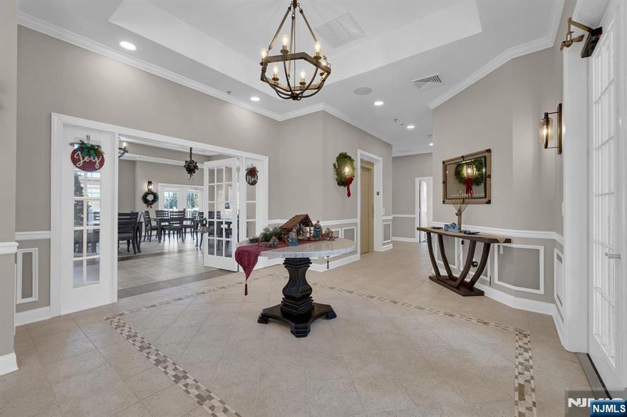 Enjoy effortless living in this desirable active adult community offering a clubhouse, pickleball courts, fitness center, pool, scenic walking paths, and more. This well-appointed first-floor condo provides easy, step-free access from the main entry ideal for everyday convenience. Thoughtfully positioned, the unit enjoys peaceful wooded views from the kitchen, living room, bedrooms, and enclosed porch, creating a private, natural backdrop. Inside, the open kitchen features ample cabinetry, updated appliances, and generous counter space perfect for both daily living and entertaining. The bright dining and living room combination is filled with natural light and opens directly to the balcony. Just off the living area, a versatile bonus room offers flexibility as a home office, den, or creative space to suit your needs. The primary suite includes a walk-in closet and an updated walk-in shower designed for comfort and ease. The second bedroom also features a walk-in closet and its own full bath, ideal for guests. A dedicated laundry closet with full-size washer and dryer (all appliances included) provides excellent storage as does the pantry. Additional highlights include an assigned garage space,guest parking directly in front, private storage unit for seasonal items, and elevator access within the building.With a spacious layout, smart floor plan, and access to resort-style amenities, this home delivers both comfort and convenience.Some photos digitally enhanced.