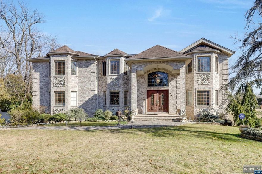 Live like royalty in this majestic Paramus palace boasting 7500 sq ft of luxury. The 2-story grand foyer welcomes you with a custom mahogany staircase and distinguished chandelier. The first floor continues with an expansive chef's kitchen, a large living room with granite gas fireplace, a tranquil sitting room, and formal dining room with a gorgeous imported chandelier from Murano Italy. Finishing the first floor is a separate living quarters with two bedrooms, one full bathroom, serene sun room, and laundry room. The second floor features an expansive primary suite with a nursery, sitting area, and a lavish spa-like bath, and continues with three additional bedrooms and full bathroom. The unfinished ground level offers 2000 sq ft with walkout yard access and endless possibilities for additional living space. Outside, the enchanting backyard oasis beckons with a spacious deck overlooking the fenced yard, and the lush landscaping provides over 1/2 acre of peace and privacy.