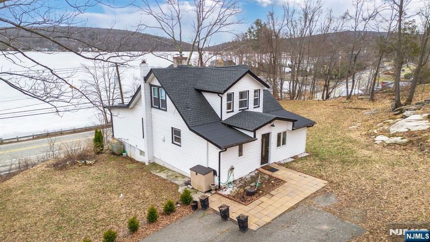 Located in the desirable West Milford Upper Greenwood Lake community, residents have the option to join a private powerboat lake association offering beach access, a boat ramp, and clubhouse amenities enhancing an already exceptional lake lifestyle.Amazing lake views set the stage for this sun-filled 3-bedroom, 2-bathroom retreat overlooking Upper Greenwood Lake. Featuring a huge living room with a striking stone fireplace, real wood floors, and expansive windows, this home offers one of the highest and widest panoramic lake and mountain views in the area truly unforgettable.The open and spacious layout is flooded with natural sunlight and designed for both relaxation and entertaining. Enjoy early morning coffee on the large deck or afternoon barbecues on the back patio, all overlooking more than a half-acre of beautifully landscaped property with ample parking. The primary bedroom is conveniently located on the first floor, while the second level offers two additional bedrooms and a dedicated office ideal for remote work or guests.Owned and meticulously re designed by the owner of a successful construction company, this home has been fully updated over the past few years. Improvements include a new roof, custom outdoor drainage, heated floors, updated bathrooms, and thoughtfully designed windows that perfectly frame the breathtaking scenery.Imagine boating, swimming, sailing, fishing, and forming lifelong friendships this is more than a home, it's a lifestyle.