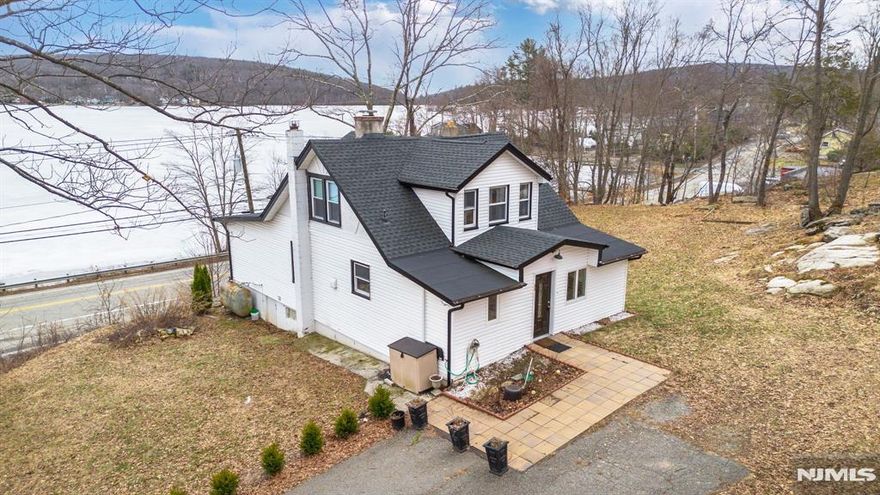 Located in the desirable West Milford Upper Greenwood Lake community, residents have the option to join a private powerboat lake association offering beach access, a boat ramp, and clubhouse amenities enhancing an already exceptional lake lifestyle.Amazing lake views set the stage for this sun-filled 3-bedroom, 2-bathroom retreat overlooking Upper Greenwood Lake. Featuring a huge living room with a striking stone fireplace, real wood floors, and expansive windows, this home offers one of the highest and widest panoramic lake and mountain views in the area truly unforgettable.The open and spacious layout is flooded with natural sunlight and designed for both relaxation and entertaining. Enjoy early morning coffee on the large deck or afternoon barbecues on the back patio, all overlooking more than a half-acre of beautifully landscaped property with ample parking. The primary bedroom is conveniently located on the first floor, while the second level offers two additional bedrooms and a dedicated office ideal for remote work or guests.Owned and meticulously re designed by the owner of a successful construction company, this home has been fully updated over the past few years. Improvements include a new roof, custom outdoor drainage, heated floors, updated bathrooms, and thoughtfully designed windows that perfectly frame the breathtaking scenery.Imagine boating, swimming, sailing, fishing, and forming lifelong friendships this is more than a home, it's a lifestyle.