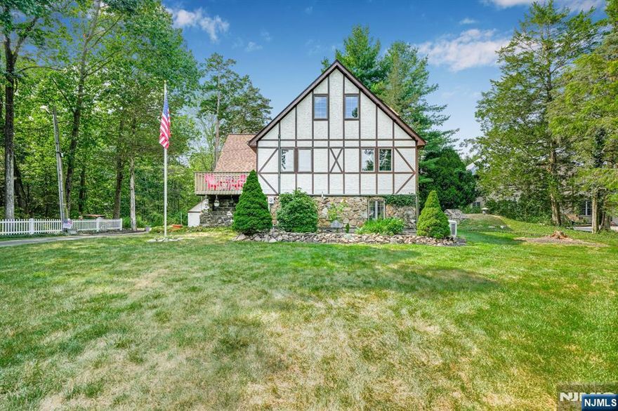 Step inside this rare and charming 4-bedroom, 4-bathroom Tudor set on over 2 acres of serene property with possible subdivision potential. This elegant home boasts an open floor plan with spacious rooms, gleaming hardwood floors, and two balconies offering picturesque views. The inviting living room features a cozy wood-burning stove and flows into the formal dining room with sliders leading to a large deck with built-in seating perfect for entertaining. The eat-in kitchen offers a breakfast bar, pantry, and easy access to a full bathroom, laundry room, and storage space. Upstairs, the spacious primary bedroom includes a full bath, walk-in closet and private balcony. Two additional bedrooms share the main bath and one features its own balcony. The third floor features a large fourth bedroom, full bath, and family room ideal for guests, a home office, or flex space. Located close to top-rated schools, NYC transportation, shopping, and excellent restaurants, this one-of-a-kind property offers a rare combination of character, space, and future potential.