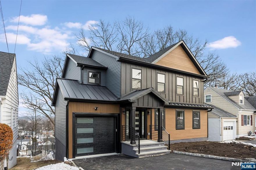 This spectacularly expanded residence has been meticulously renovated with exceptional attention to detail throughout. The modern open-concept floor plan is highlighted by beautiful oak floors, abundant natural light, and a seamless connection between the spacious living and dining areas. The expansive kitchen overlooks the main living space and features a sleek modern electric fireplace, creating a warm yet contemporary ambiance. A well-appointed first-floor bedroom with a private en-suite bath offers flexibility for guests or multi-generational living, complemented by an elegant powder room on the main level. The second floor is anchored by a generously sized primary suite showcasing winter skyline views of New York City and a luxurious spa-inspired bath with a soaking tub and oversized glass-enclosed shower. Three additional well-proportioned bedrooms and a stunning hall bath complete this level. The lower level offers a large family or recreation room, utility space, and walkout access to a beautifully designed, mostly covered patio overlooking the yard. Truly move-in ready, this home reflects thoughtful craftsmanship and refined finishes at every turn.