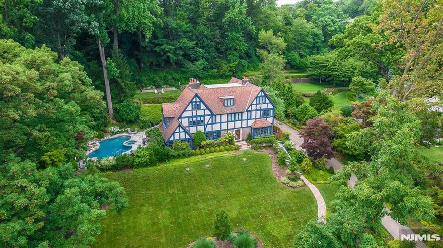 Perched on a sweet spot of Highland Avenue sits this elegant Tudor style home that defines love where you live. Unmatched skyline views can be enjoyed in all four seasons. Lush landscaping sweeps you up the property leading to the stately front entry and welcomes you home, where exquisite architectural details are found at every turn. The first floor features a spacious living room w/fireplace, leading to the sunroom with views to the in-ground Gunite heated pool with waterfall feature. The custom lighting and landscaping will make you feel like you're in Shangri-La in Montclair. Library, formal dining room, private powder room, cooks kitchen and breakfast room w/gas fireplace complete the first floor. The kitchen has high end appliances, including a double Wolf stove and SubZero fridge. All bedrooms are ensuite and many of the baths have heated floors. The luxurious primary suite features a spacious bedroom with sitting room and dressing room with walk-in closet. From the kitchen you can access a second staircase leading up to two bedrooms and a full bath. Ideal floorplan for a guest suite or au pair. Endless possibilities in this flexible floorplan. Lower level gym and steam room - ditch your gym membership! This home is made for entertaining. A showpiece that also feels like home. Additional amenities include a generator, 3 car garage with pollinator garden above, newer AC units, and more. Come and experience true pride of ownership where no detail has gone overlooked.