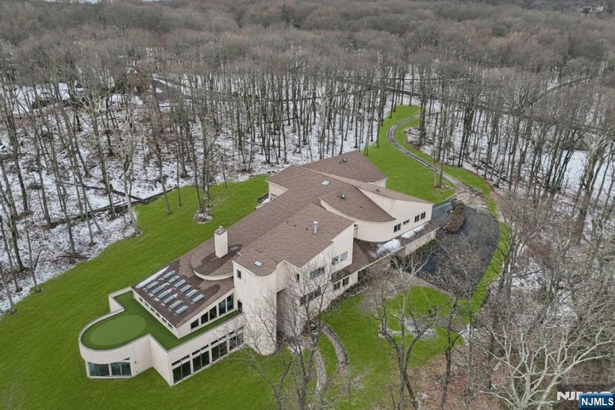 A rare architectural statement where scale, sophistication, and elevated luxury converge. Set on 3.7 private acres, the residence spans approximately 13,000 sq ft with 7 bdrms, 7 full baths and 2 half baths, designed for both grand entertaining and refined everyday living. From arrival, striking architectural lines, dramatic volume, and curated sightlines create a 'WOW' factor. The grand living room unfolds as a stunning open-concept space with soaring 32-ft ceilings, a sculptural spiral staircase, and a 2-sided 16-ft gas fireplace. Floor-to-ceiling windows flood the home with natural light, while views extend to the sun-drenched, heated indoor pool. The chef's kitchen pairs performance with modern design, featuring Wolf and Sub-Zero appliances, multiple ovens, wine refrigeration, coffee system, and premium finishes throughout. The main level also offers a private theater, gym, office, and first-floor au pair ensuite. The second level is anchored by a luxurious primary suite sanctuary with 20-ft ceilings, dual balconies, loft, sitting room, dual walk-in closets, and a spa-inspired bath with separate water closets and bidet. 4 addt'l bdrms include 3 ensuites and private balcony access.The lower level showcases the indoor pool, a 1,200-sq ft ballroom, dry sauna, full bath, and flexible space ideal for a wine room, cigar lounge, or recreation area. Additional highlights include a 4 car heated garage and dedicated elevator shaft. A truly one-of-a-kind Mendham estate!