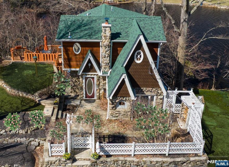 Welcome to the "Gingerbread House" built in 1936, with approximately 135 feet of private lake frontage and private dock. Original moldings, beams and wainscoting have been restored to their original grandeur. This 3 Bedroom 1.5 Bath home is fully renovated, perched on an oversized lot upon Upper Greenwood Lake. It offers Old-World charm with all modern amenities. The large kitchen is a chef's dream with all new stainless-steel appliances; it is truly the heart of this home. There is an adjacent sitting area/home office and a Hearthstone soapstone wood stove with new liner. The spacious living room has a renovated half bath and stacked washer dryer. Directly off the living room is a huge balcony overlooking the lake and mature trees giving privacy and a tree house feel. Walk up to the second level to find 3 spacious bedrooms with lake views and an oversized renovated bathroom with new skylights and soaking tub. Just minutes from Warwick NY wineries, farms, drive-in movie, hiking and skiing. Come enjoy private decks, your own dock, fire pit and everything Upper Greenwood Lake, a private lake community, has to offer. Power boats, jet skis, fishing and a beautiful Clubhouse and beach. *2 Bedroom Town Verified Septic NEW*