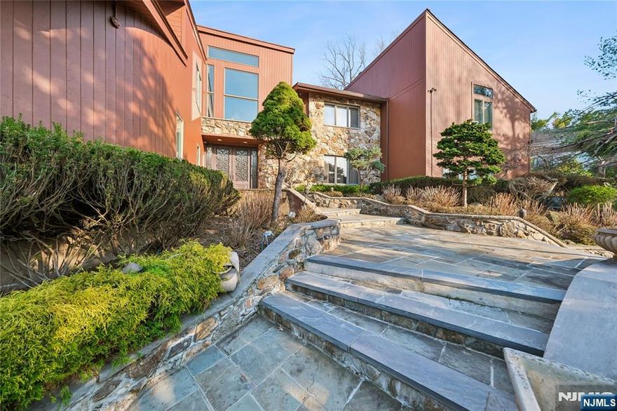Welcome to this grand 7-bedroom manor located in the prestigious East Hill of Cresskill, situated on nearly an acre of land. The impressive open-entry foyer flows seamlessly into a spacious living area, featuring a built-in bar designed for hosting and sophisticated entertaining. The thoughtful layout includes a coveted first-floor primary suite, providing convenience and privacy. Retreat to a spectacular resort-style backyard, an outdoor oasis complete with an in-ground pool, hot tub, and a cascading waterfall. The expansive property also includes a full finished basement, offering a versatile blank canvas for a home gym, play area, or secondary recreation space. This is a rare opportunity to enjoy luxury living with a private, vacation-like setting in a prime Bergen County location.