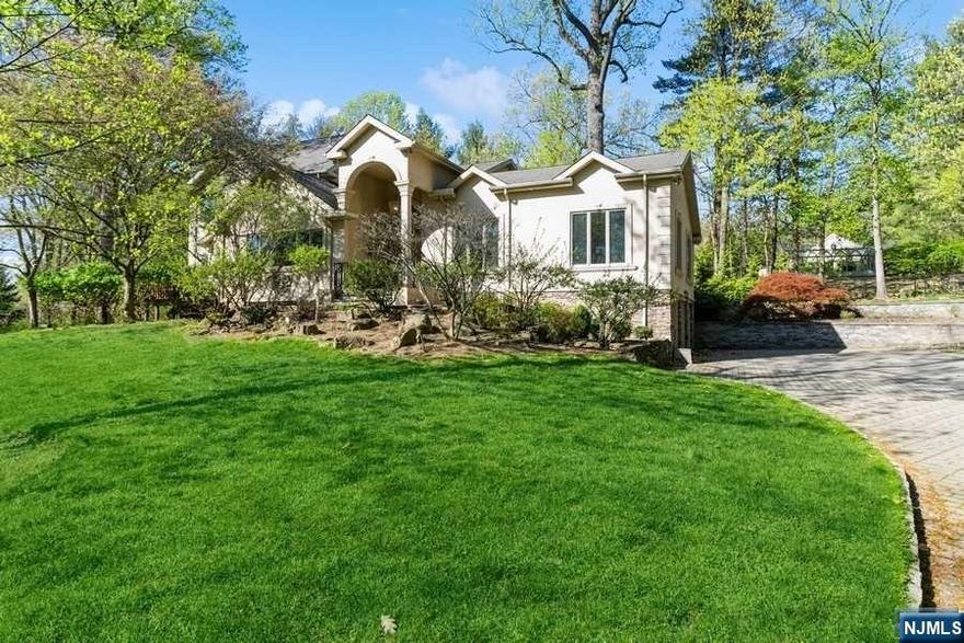 Majestically set on a private one full acre and sitting high on Tenafly's East Hill, this 5-bedroom home offers a bright, open floor plan. Featuring cathedral ceilings, stunning mahogany doors, chef kitchen with top-of-the-line appliances and a breakfast area with magnificent views of the park like property. Large primary suite has spa like marble bath with radiant heated floors, jacuzzi tub, double vanity and water closet. Full finished lower level find large rec area, bedroom, full bath and access to 3 car garage. Minutes from NYC blue ribbon schools. A MUST SEE!