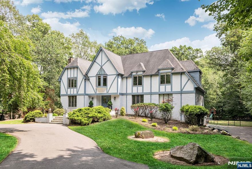 Welcome to this Tudor-style residence offering five bedrooms and six baths. A grand foyer with a sweeping staircase introduces the main level, designed for both entertaining and everyday living. The light-filled great room features a stone fireplace and large windows, while an adjoining sunroom with a custom wet bar creates the perfect gathering spot. The eat-in kitchen boasts a center island, stainless steel appliances, an oversized refrigerator, and double ovens, and opens to a spacious deck overlooking serene grounds. Formal dinners are hosted in the elegant dining room, while a cozy living room with its own fireplace provides a tranquil retreat. Also on this floor are a laundry room, powder room, home office, and a bedroom with an ensuite bath. Upstairs, the primary suite features two walk-in closets and a spa-like bathroom with a soaking tub and separate shower. An additional ensuite bedroom plus two bedrooms sharing a hall bath complete this level. The walk-out lower level offers flexible recreation space, a gym, a powder room, and a covered patio. Outside, a private oasis awaits with a gunite pool edged in travertine decking and surrounded by lush landscaping. Classic charm meets modern amenities in this exceptional luxury home, ideally located close to schools, NYC transportation, and downtown Allendaleâ€”donâ€™t miss making it yours!