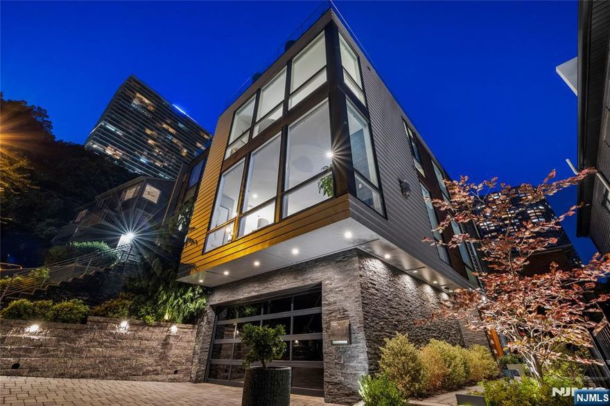 A Modern Masterpiece with Skyline Views > This south facing home sits on an oversized 60x89 lot affording more interior living space + width than most duplexes. With soaring 12" ft ceilings and floor-to-ceiling windows, the home is bathed in natural light, though the extra large windows. The unique architecture is immediately noticed upon entering through double doors to a dramatic glass ceiling above. The open-concept second floor flows through the family room, dining/LR, & anchored by a sleek floating staircase. The Chef's kitchen features an 11" ft marble island, custom cabinetry, Sub-Zero & Wolf appliances, walk-in pantry. Upstairs the primary suite captures NYC views and includes dual walk-in closets, a spa-inspired bath with soaking tub, & dual rain showers. The private roof terrace has Mid Town views, gas fire pit, built-in speakers, and hose access. Additional Features Include: Professionally landscaped lot with full irrigation system, Designer bathrooms by Porcelanosa with radiant heat, 2 car garage with a second washer/dryer unit, Full smart home automation with 6 zone Lennox HVAC and touchscreen panels, Built in audio system with speakers in every room, plus outdoor zones, Seven wall mounted TVs throughout, Central vacuum system, Nice smart security system with five exterior cameras and mobile enabled control, Skylit floating stairwell and radiant heated floors throughout. This custom built home is the epitome for luxurious modern living.