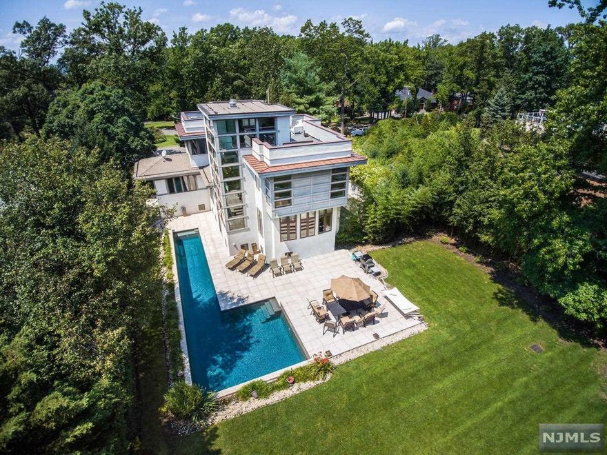 Nestled on one of Englewood East HIll's most desirable streets is this spectacular sleek modern four bedroom ,four and one half bath home completed in 2006 with 3+ car garage and high tech amenities.Set on over half an acre this home is a true oasis offering a backyard retreat which includes a magnificent heated gunite poo and lushly landscaped yard. High ceilings, open floor plan and glass banisters make this home perfect for modern day living. Enjoy the twelve seat screening room with projection system and surround sound . The chef's kitchen with floor to ceiling custom cabinets includes Viking Refrigerator/Freezer, Viking cooktop and Viking Oven. A dumbwaiter elevator conveniently transfers your groceries from the 3+ car garage to your granite kitchen counter. The stunning master bedroom suite offers his/hers large walk in closets ,master bath with a custom stone soaking tub , spalike shower and radiant heated floors.This home is a must see just 6 miles to New York City