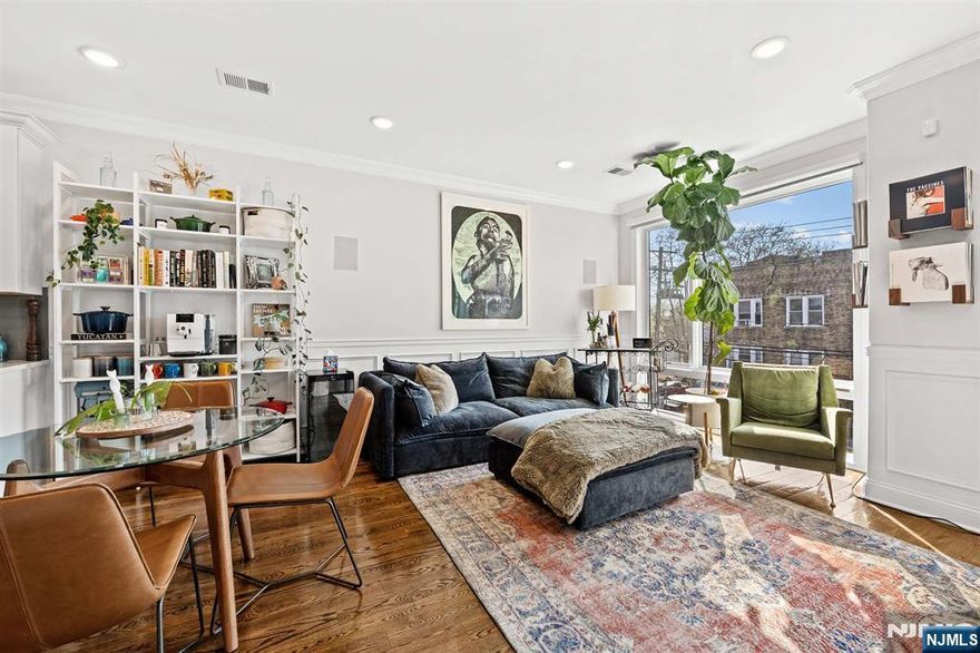 This expansive and meticulously maintained 3-bedroom, 2-bathroom residence is flooded with natural light and offers a large private roof deck with panoramic NYC views. Oversized Pella windows enhance the bright, open feel, while thoughtful upgrades include central heating and A/C, a video intercom system, and built-in home theater speakers. The primary suite features a walk-in closet and a beautifully finished en-suite bathroom. Both bathrooms are outfitted with floor-to-ceiling Porcelanosa tile. The modern kitchen is designed with quartz countertops, a waterfall island, Oxford latte white cabinetry, and LG black stainless-steel appliances. Additional highlights include hardwood floors, wainscoting throughout, recessed lighting, and generous closet space, including a walk-in closet in the second bedroom and a storage closet on the rooftop. This home also includes a deeded tandem parking spot along with two large bonus storage closets in the garage. Ideally located in the heart of Jersey City Heights, with easy access to shops and restaurants and a bus stop right down the street allowing for convenient access to NYC and PATH train.