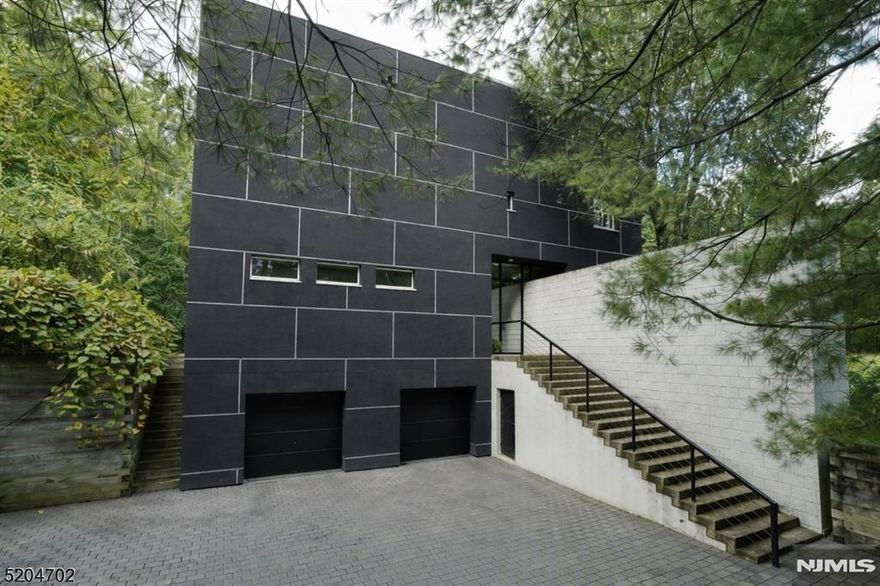 A rare architectural statement set amid serene privacy and expansive grounds, this extraordinary residence by UKZ Architects introduced Modernism to North Caldwell just 19 miles from New York City. Celebrated and award-winning, the home is conceived as a livable work of art, defined by two intersecting L-shaped planes that frame the landscape and dissolve the boundary between indoors and out. The architecture invites nature into the experience of daily living, with a sculptural garden wall draped in wisteria that guides the eye from exterior to interior. Clean lines, intentional sightlines, and a seamless connection to the surrounding land create an atmosphere of quiet sophistication and retreat.The renovated kitchen is a study in modern functionality, featuring a Wolf range, oven, and microwave, Miele dishwasher, and Sub-Zero refrigerator perfectly suited for both everyday living and elevated entertaining. The private primary suite offers a tranquil escape, complete with a redesigned spa-inspired bath.Tucked away yet effortlessly connected to Montclair's dining, culture, and NYC train and bus service, this home offers the rare opportunity to live immersed in modern design, privacy, and nature where architecture, art, and lifestyle converge.