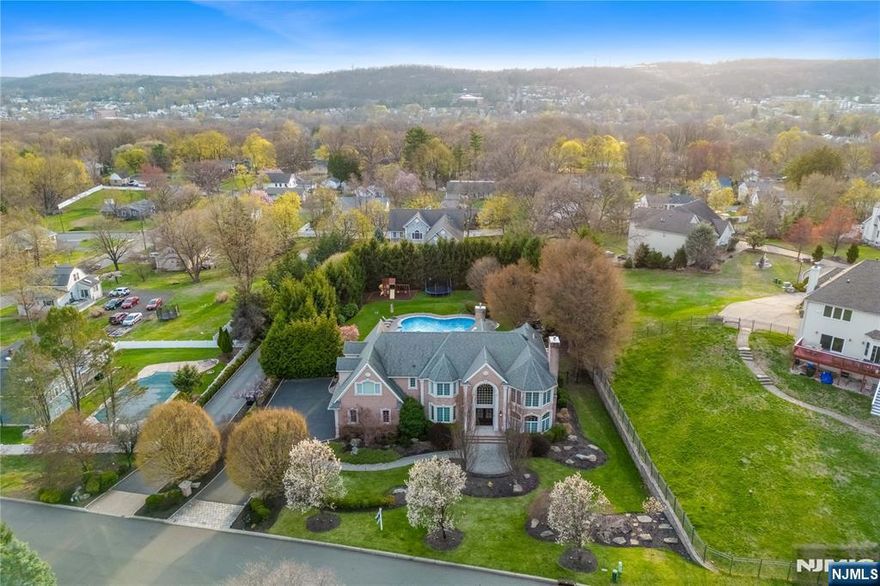 Situated on one of North Haledon's most desired cul-de-sacs is this incredible brick estate, featuring 7,500 feet of beautifully finished living space on a perfectly manicured 2/3 acre. Enter through the grand two-story foyer and enjoy elegant formal living and dining rooms, a dramatic great room with soaring ceilings and fireplace, massive eat-in chef's kitchen with additional living room, and main floor bedroom with full bathroom. Upstairs, a luxurious primary suite on its own wing, with 3 more bedrooms including another bedroom suite. The sprawling basement includes a recently added bar, a gym, home office, full bathroom and more. Outside, entertain in your resort-style backyard featuring a heated pool, spa, outdoor kitchen, koi pond, and playground, encased by lush landscaping and matured privacy trees. Additional highlights include custom millwork, oversized 3 car garage, water feature, and smart home upgrades. Located near parks, top rated schools, easy commute to NYC.