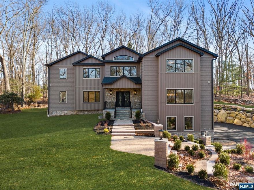 Introducing a stunning new construction in Ramsey, NJ. Nearly 8,000 sq ft of living space on 1.4 acres of private, secluded land. This five bedroom, 6.5 bath masterpiece features radiant heat in all baths and kitchen, top tier plumbing and electrical, and custom walnut woodwork throughout. Enjoy a chef's kitchen with double islands, a butler's pantry, and a wine room. Each bedroom offers custom closets, and the oversized second floor laundry adds convenience. Two fireplaces, two mudrooms, and a fully finished basement with a full bath complete the interior. Smart home technology includes pre wiring for TVs, whole home automation, video intercom, and a six zone in ceiling audio system. The exterior is board and batten with a 3 car garage and long, private driveway. In the backyard, you'll find a flat yard and patio. Take advantage of Ramsey's new low taxes. This is the home you've been waiting for!