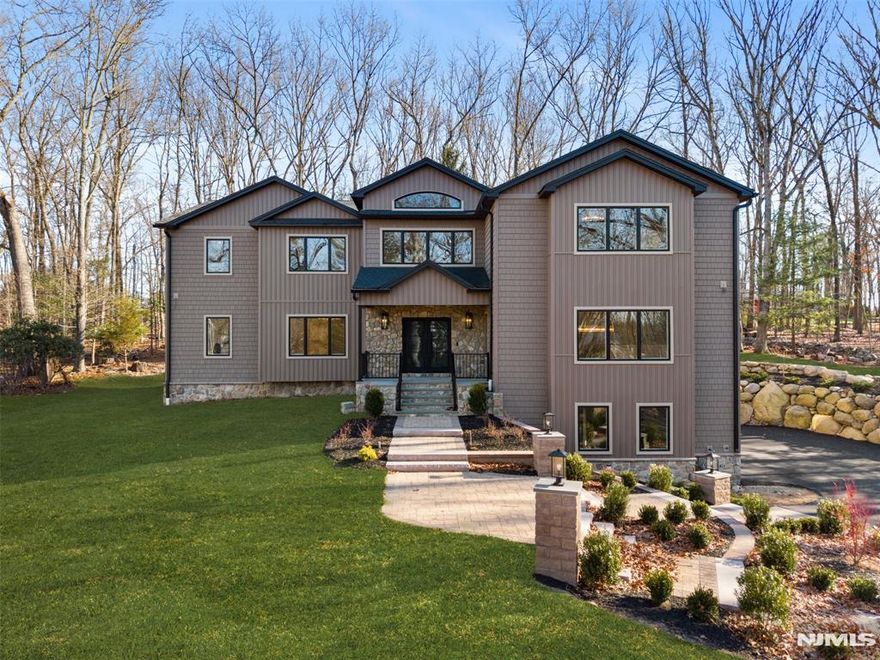 Introducing a stunning new construction in Ramsey, NJ. Nearly 8,000 sq ft of living space on 1.4 acres of private, secluded land. This five bedroom, 6.5 bath masterpiece features radiant heat in all baths and kitchen, top tier plumbing and electrical, and custom walnut woodwork throughout. Enjoy a chef's kitchen with double islands, a butler's pantry, and a wine room. Each bedroom offers custom closets, and the oversized second floor laundry adds convenience. Two fireplaces, two mudrooms, and a fully finished basement with a full bath complete the interior. Smart home technology includes pre wiring for TVs, whole home automation, video intercom, and a six zone in ceiling audio system. The exterior is board and batten with a 3 car garage and long, private driveway. In the backyard, you'll find a flat yard and patio. Take advantage of Ramsey's new low taxes. This is the home you've been waiting for!