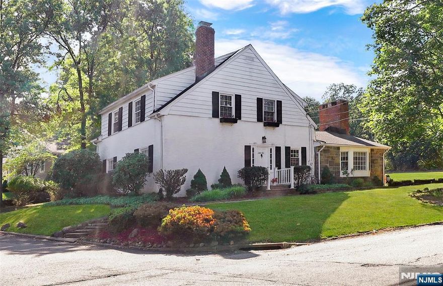 A Great Notch classic, this Custom Colonial offers timeless character alongside thoughtful updates in one of Little Falls' most sought-after neighborhoods. The centerpiece of the home is defined by an expansive great room with cathedral wood-beamed ceilings, a dramatic brick fireplace "wow wall" with oversized windows that bring in abundant natural light and a home bar. The dining room with sliding doors opens directly to the patio, creating an easy connection to the bucolic outdoors. A seamless flow connects the dining area to the updated light-filled kitchen finished with granite countertops, pantry, desk area, SS appliances, a center island and cabinets galore providing functionality. Upstairs and down, the layout offers four flexible bedrooms that can serve as guest spaces, private retreats and home offices with a full basement for laundry & storage. Primary suite with fireplace currently located on main level. Additional highlights include hardwood floors, closet space a plenty, a two-car attached garage on Notch Park Road offering driveway-direct kitchen access. The landscaped corner lot adds curb appeal and large yard space. Steps away are peaceful nature trails for daily walks, hikes or bike rides. NYC only 16 miles away, a bus stop within walking distance and Montclair State University train station, the location is a commuter's dream. A night out in Montclair or a hike through the Mills Reservation, you are minutes from both city energy & natural escapes.