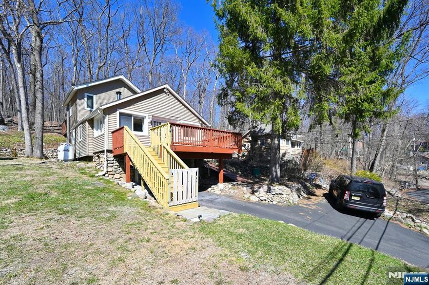 Awesome lake house in Shady Lake West Milford! This home has true lake house charm everywhere you look! Log interior-wood beams- Gorgeous wood flooring throughout- Wood burning stove. Updated 1st floor bathroom -jacuzzi tub- Upstairs is the big main bedroom with its own bathroom and deck, Natural wood beams and built in lighting above bed. The backyard is nestled right up against a pretty mountain and side yard is fenced in. Enjoy nature at its finest hanging out on either the backyard or front yard deck!. Home has a young roof, brand new staircase to the front yard deck, washer/dryer on main floor with additional hook-up in garage. Don't miss this opportunity to be apart of all that West Milford has to offer! Shady Lake is conveniently located in lower West Milford, close to highways and shopping. Home is currently being used as a 3 bedroom but has a 2 bedroom town verified septic.