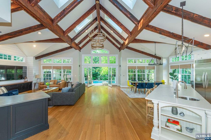 The jaw-dropping great room is the heart of this comfortable yet expansive custom colonial, w/ soaring cathedral ceiling, open floor plan boasting spacious living area w/ wet bar, dining space & chef's kitchen w/ plenty of cabinetry, high end stainless steel appliances, quartz counters & pantry. Backyard oasis w/ in-ground pool, year-round hot-tub, lights and landscaping designed to bloom all spring/summer w/ mature trees for privacy. 1st fl also features an elegant office, playroom & leisure area. 2nd fl boasts large primary suite w/ juliet balcony overlooking great room, walk-in closet, stylish en-suite bath w/ double vanity, double shower & soaking tub, plus 2 sizable bedrooms & hall bath. 3rd flr has 2 more bedrooms & full bath. Finished basement rec room, 1/2 bath & wine cellar, along w/ 2 car garage & attached exercise room all but complete this perfect meld of turn-of-the-century details & modern convenience! Close to shops, train to NYC, etc. + whole house generator incl.