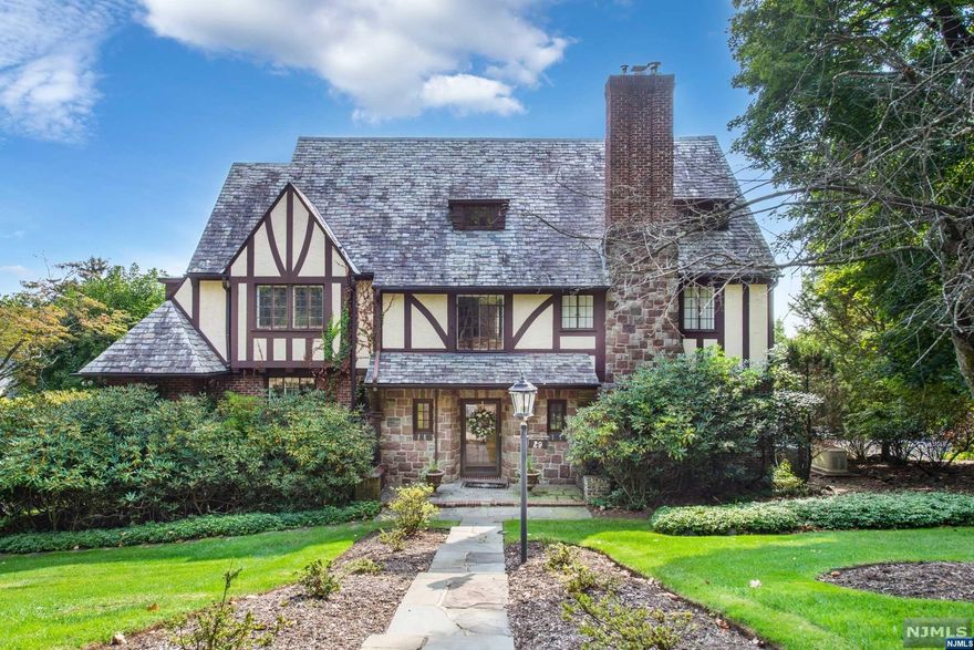 Follow the yellow brick road up the mountain to a large sundrenched Tudor with gorgeous skyline views. Elegant space includes bright two story entrance hall and original details throughout, including built-ins, boxed beams, flat arches, and gorgeous hardwood floors. The large picture casement windows on every floor all have custom interior storm windows. The home features numerous rooms, such as a library, solarium, mini greenhouse, wine bar, billiard room, and potential home office spaces on every floor. The four second floor bedrooms all have ensuite baths, and half baths for guests on first and ground floor. Mudroom / laundry room is also convenient to attached garage and terrace entrance. EIK kitchen has adjacent foyer, butler pantry, breakfast nook. Many thoughtful updates include Koi pond with fountain, lawn sprinkler system, newer furnace and cac. a zen masterbath with huge walk-in closet, 3rd floor media room, whole house generator, and wine bar. NYC bus at corner