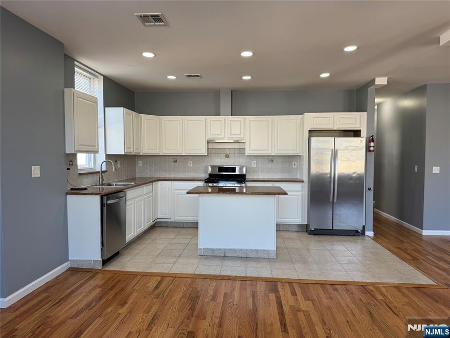 Discover this stunning 2,100 SqFt, third-floor apartment in the heart of Kearny, New Jersey! This bright and spacious apartment features four bedrooms, including a large master suite, and two full bathrooms, making it perfect for anyone that loves extra space. The open-concept layout seamlessly connects the kitchen, dining, and living areas, creating a modern and welcoming environment. The kitchen is a chef's dream, equipped with stainless steel appliances, an island with additional seating, granite countertops, and ample cabinet space for all your storage needs. The combined dining and living room area is expansive, offering the perfect space for entertaining and relaxing. This home boasts beautiful hardwood floors, recessed lighting, central air and forced heat, ensuring comfort year-round. Storage is abundant with plenty of closet space, and the numerous windows fill the apartment with natural light throughout the day. Additional conveniences include a brand-new in-unit washer and dryer and an intercom system for secure front-door communication. Situated in a prime location just blocks from Kearny Avenue, this apartment is close to shopping, dining, schools, parks, and houses of worship. Public transportation is a breeze, with bus stops right at the corner, major highways nearby, and the Harrison PATH Train Station only 2.6 miles away. This is truly a commuter's dream! Don't miss the opportunity to make this exceptional apartment your new home!