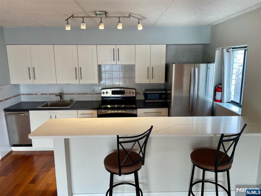 Welcome home to this bright and spacious corner one-bedroom apartment offering comfort, convenience, and location. Enjoy a private balcony, in-unit laundry, and a modern kitchen with stainless steel appliances, including a dishwasher, and a newly installed quartz countertop island. The fitness room is located on the same floor, along with a storage unit, and the building offers elevator access from the ground floor. One covered parking space included. Updated heating and air conditioning units throughout. Conveniently located near major highways and public transportation, providing easy access to NYC, and just 3 blocks away from the shops and restaurants along Main Street in Hackensack.