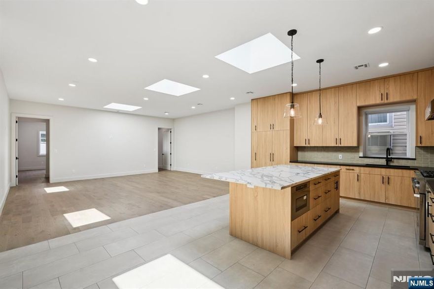 Stunning Warehouse Conversion â€“ Expansive Mother-Daughter Home with Designer Finishes Welcome to this beautifully converted warehouse, now a breathtaking mother-daughter residence offering approximately 3,400 sq/ft of thoughtfully designed living space. Soaring 10-foot ceilings and 8-foot doors on the main level create a grand and airy ambiance, while oversized windows and three skylights flood the space with natural light. The heart of the home is the custom chefâ€™s kitchen, featuring a large island with seating for six, sleek Dacor appliances including a 36" gas range, counter-depth refrigerator, and integrated dishwasherâ€”all seamlessly clad in matching cabinetry. The open-concept layout connects the kitchen to an expansive living and dining area, ideal for entertaining. A stylish half bath is conveniently located for guests. Throughout the home, you'll find 5" wide-plank hardwood and imported Italian tile flooring. The luxurious primary suite includes a walk-in closet and private en-suite bath, while two additional bedrooms share a spacious Jack and Jill bathroom. Step outside to a fully finished backyard oasis complete with pavers, privacy fencing, and both gas and electric hook-upsâ€”perfect for outdoor gatherings. The lower level offers a separate living space, ideal for extended family or guests, with its own bedroom, full bath, kitchenette, laundry room, and a massive entertainment area surrounded by custom cabinetry and storage. Every inch of this home has been