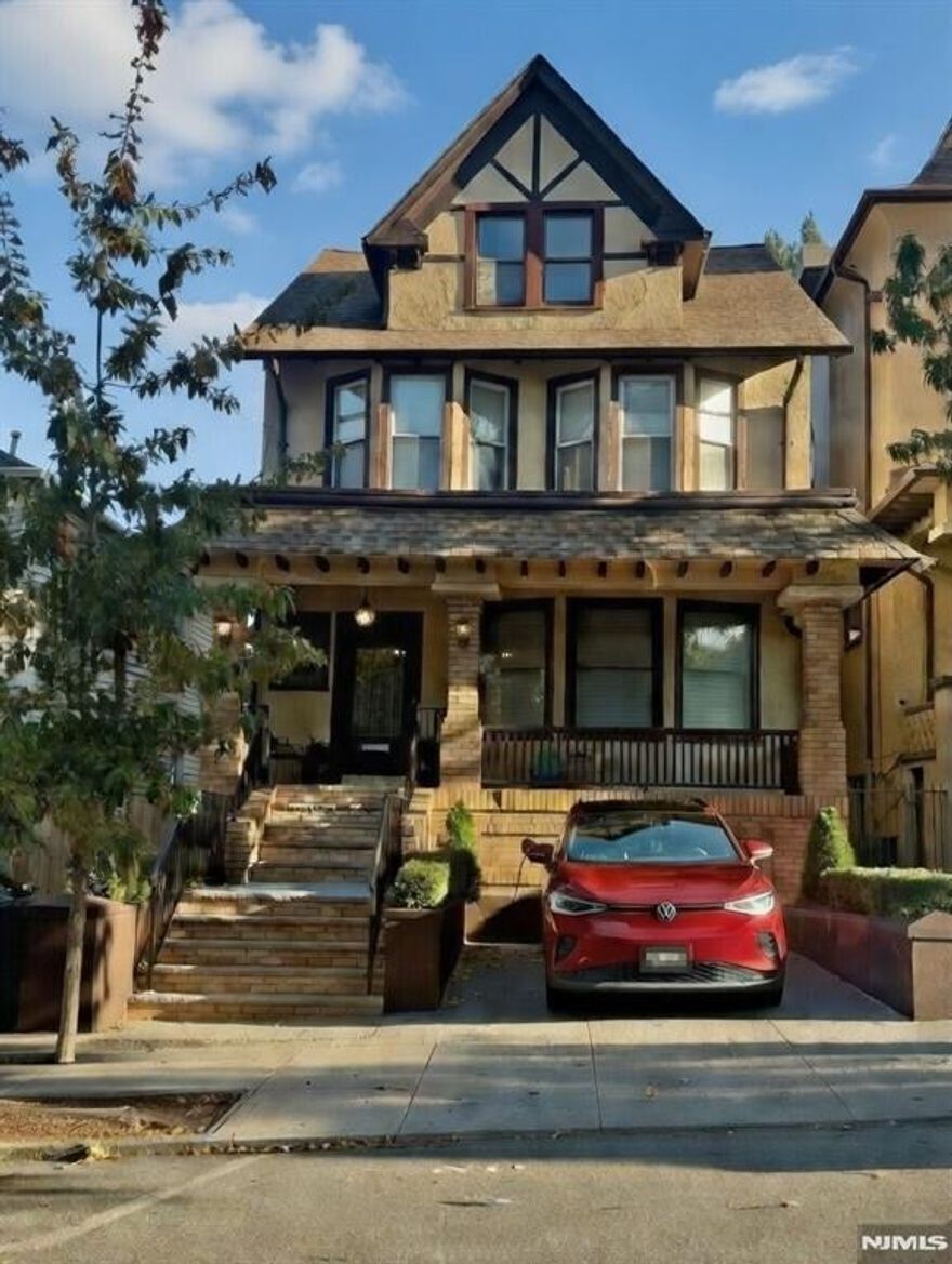 Set on a full 29 x 105 lot in Jersey City's McGinley Square, this grand Tudor Victorian offers a rare combination of scale, modern renovations and location seldom found this close to NYC. With 7 bedrooms and 3 bathrooms, the home features a renovated kitchen, central air conditioning, and new systems including all new electrical, providing modern comfort & peace of mind. These thoughtful upgrades are beautifully complemented by preserved architectural details including stained glass, parquet floors, restored woodwork, and elegant pocket doors. The main living spaces are expansive yet inviting, filled with natural light from bay windows & thoughtfully designed for both entertaining & everyday living. Outside, a landscaped low maintenance yard & dedicated parking with an EV charger add conveniences rarely available with homes of this character, with additional parking possible directly in front of the driveway. The location further elevates the offering. Just a 10 minute walk to 273 acre Lincoln Park & approximately a 30 minute door to door PATH commute to the Financial District, the home provides an ideal balance of green space & city connectivity. Newark Liberty International Airport is also just a short 20 minute drive, making regional and international travel remarkably convenient. Offering exceptional interior space, outdoor living, private parking, modern renovations & close proximity to transportation and parks, this is truly a one of a kind single family opportunity!
