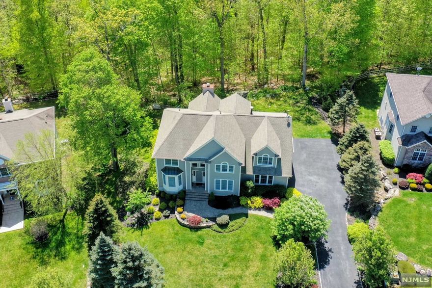 Country club living only 40 miles from NYC surrounded by parklands & the Ramapo Mountains! Custom built 4 bedrm, 3.5 bath colonial on over a half-acre of professionally landscaped property. Relax on your private deck listening to the babbling brook as your HOA fee includes lawn maintenance, tree pruning & snow removal. As you enter this impeccable, freshly painted home, you will be welcomed by a stunning two-story entry w/ dramatic balcony bridge w/ open views of the entire first floor w/ soaring ceilings. Great entertaining floorplan w/ upgraded kitchen appliances, granite counters, ample cabinetry, center island & breakfast nook overlooking spacious family rm w/ wood burning fireplace flanked w/ wall of sun-lit windows & french doors. First floor master bedrm w/ walk-in closet & gorgeous modern en-suite. Upper level has 3 bedrms/2 full bath. Walk-out lower level w/ family rm, home gym, office. Amenities include: Clubhouse, outdoor pool, tennis court & fitness ctr.
