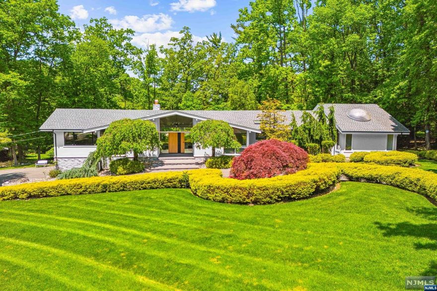 Step into this stunning mid-century modern ranch in Tenafly's prestigious East Hill. This 4-bedroom, 4.5-bathroom home sits on over an acre of beautifully landscaped grounds and features a range of upgrades. Enjoy new stucco and panel stone exteriors, and a newly replaced roof. Inside, the kitchen boasts top-tier appliances, including a Subzero fridge and freezer, Samsung cooktop and dishwasher, and a Zephyr commercial hood. The living room offers breathtaking views of the park-like backyard, while the family room with a wood-burning fireplace opens to an inviting patio. The master suite includes a walk-in closet and an oversized bath plus an additional bathroom. Additional features include a new deck, newer Pella windows, a whole security camera system with ADT, central vacuum in bedrooms, and a secondary mini-split system for the basement.