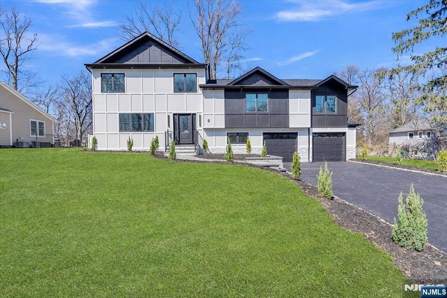Welcome to this original foundation, new construction tri-level split in the highly sought-after town of Woodcliff Lake! Offering multiple levels of spacious living, this home features engineered hardwood floors, multi-zone central air and forced heat, recessed lighting, and a two-car garage. The main level has a double story foyer and half bath, also boasts a bright and open layout with a spacious dining room featuring an electric fireplace insert, and a large kitchen complete with stainless steel appliances, soft-close cabinetry, a five-person breakfast bar, adjacent bar area, and a walk-in pantry equipped with a second sink and dishwasher. The expansive living room is filled with natural light from oversized windows and a sliding glass door. The second level offers three well-appointed bedrooms and two full bathrooms, including a junior en-suite. All closets feature custom shelving for optimal organization. The top level is dedicated to a luxurious primary suite with two walk-in closets and a spa-like en-suite bath, including a double vanity, soaking tub, and walk-in shower. An additional bedroom with its own en-suite bath and a conveniently located laundry room complete this level. The ground level provides a versatile living space perfect for a playroom, home office, or den, along with direct access to the two-car garage and a utility room. Enjoy outdoor living in the huge, fully fenced backyard featuring a Trex deck, all situated on a dead-end street. Donâ€™t miss this!