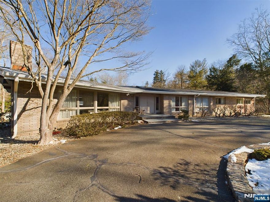 Nestled by a picturesque river, this 3,664 sq. ft. ranch-style home offers spacious interiors and outdoor serenity on over an acre. Welcoming entry hall connecting to formal living with stone fireplace and formal dining room, a modern eat-in kitchen, and a cozy family room with another fireplace. This home boasts a spacious primary suite with an ensuite bath, three additional bedrooms, and two versatile bonus rooms. Abundant windows fill the home with natural light. A massive full, unfinished basement with endless potential complete this home. Outdoors, enjoy a large Gunite pool and beautifully designed Japanese-inspired gardens, creating a serene entertainment space. The sale includes over $20,000 in architectural plans for potential redevelopment. Conveniently located near public transport, this property combines prime location with substantial potential, making it a compelling opportunity for your dream home. Bus to all Ridgewood schools.