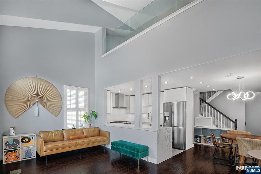 Spacious modern home with elegant upgrades. Popular Chatham style floorplan with two bedrooms and a huge loft with sliding glass door that can be used as third bedroom, home office or entertainment area. High ceilings and oversized windows facing South provide sunlight all day long. Norman shutters adorn every window for added privacy and style. A modern quartz waterfall island in the kitchen, complemented by sleek white cabinets and stainless steel appliances. One of only few homes with a stove that vents out. Beautiful solid cherry wood floors throughout the entire home. Convenient laundry on the bedroom level. Built-in closets throughout. Parking for two cars; one in private garage and one in driveway. Sought after community features two pools with jacuzzis, children's playground, waterfront promenade and free shuttle bus to Ferry and Light Rail. Steps to 158 bus to NYC. Close to restaurants and shopping. This home is a haven of luxury and practicality, offering everything you need for comfortable living. Perfectly suited for families or professionals seeking a stylish and functional space.