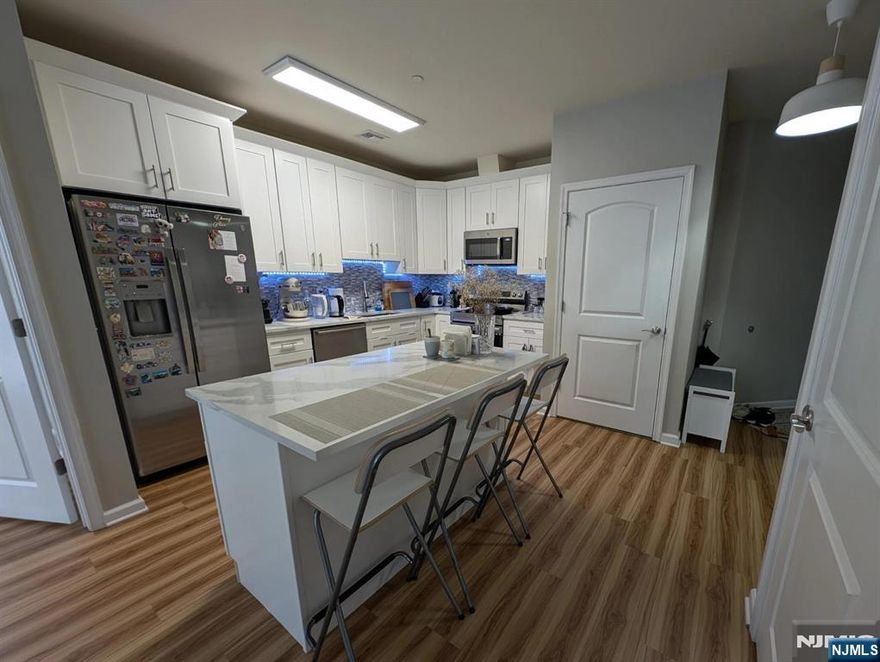 Bathe in natural light in this stunning southwest-facing corner residence. This spacious, updated 2-bedroom, 2-bathroom home features a primary suite complete with a walk-in closet and a private full bath. Modern convenience meets efficiency with in-unit laundry and integrated Smart Home technology, including a smart stove, Nest thermostat, and secure keyless entry. Forget the stress of street parking with your own dedicated garage space. Located in a LEED-certified building, you are perfectly positioned for an effortless commute just a 25-minute ride to NYC via nearby public transit. Enjoy the perfect blend of suburban comfort and urban accessibility. Schedule your private tour today!
