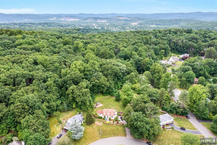 Nestled on .72 acres of lush property, this 3 Bd Rm, 2.5 Bth residence is on a quiet cul-de-sac AND backs up to park land! Enjoy unmatched privacy! Relax & entertain on the deck in the beautiful, scenic backyard. Enter into an interior illuminated with natural light & views. The Large Living Room with gas fireplace opens up to the Dining area and Kitchen featuring hardwood cabinets, granite countertops and a breakfast bar. Hardwood floors continue into the Family Room where a 2nd gas fireplace & built-in bookshelves compliment the views to the backyard. The Office/Den and Powder Rm complete the first floor. The spacious primary suite with walk-in closet & en suite bathroom connects via the hall to 2 bedrooms & the full hallway bath on the second floor. The Lower Level has the laundry & is partially finished leading to the 2 car garage & plenty of driveway parking space. Outstanding location just a short distance from downtown Oakland as well as nearby Franklin Lakes and Wayne.