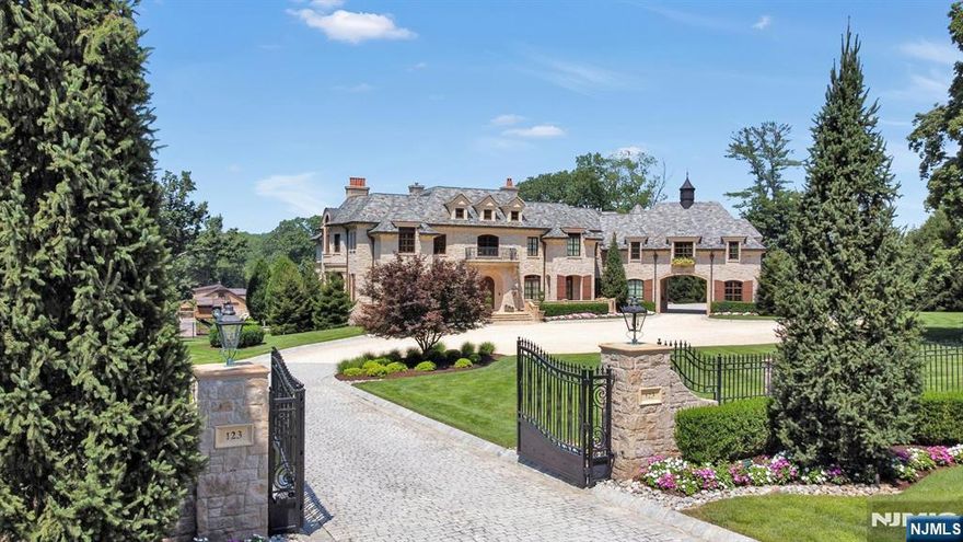 Beyond a gated approach on 4.4 serene acres, this Saddle River estate evokes a timeless French chateau, fusing refined architecture with resort living. The grounds showcase a sun splashed pool terrace with spa, formal gardens, playground, pergola and an expansive great lawn. Terraced open and covered patios span each level for seamless indoor/outdoor flow. A 4 car garage and single vehicle porte cochere complete the elegant arrival. For equestrians, a four stall stable with bonus space and fenced grass pasture/paddock elevate the offering. Inside, an elevator services three meticulously finished levels encompassing 25 rooms, 6 ensuite bedrooms, 7 full baths, and 2 guest baths. A grand foyer with sweeping staircase introduces impeccable craftsmanship and gracious scale. The main level includes formal sitting and dining rooms, a mahogany office/library with fireplace, and a family living area with informal dining and a chef's kitchen. The private primary suite features a foyer entry, fireplace, dual walk in boutique closets, a spa inspired bath, and a secluded patio; four additional ensuite bedrooms, full laundry, and a bonus room complete this floor. The walkout lower level is designed for wellness and play: a full ensuite bedroom, dual fitness rooms, massage room, sauna, media area, lounge with billiards, and a climate controlled wine cellar with tasting area. A partial kitchen opens to the covered patio and pool terrace, ideal for grand entertaining and everyday luxury.