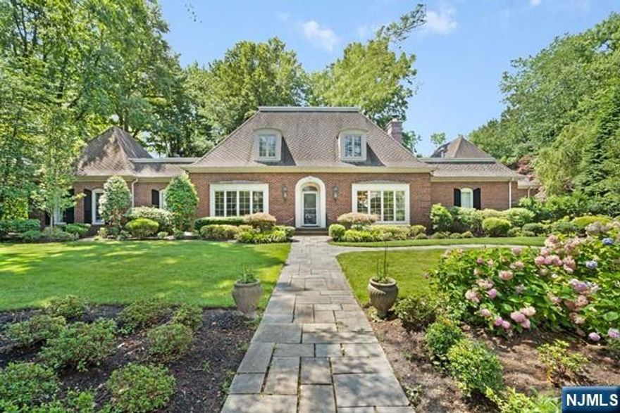Discover this elegant French Country brick estate in the coveted Holmehill Section of Roseland, just 22 miles from NYC. A blend of luxury and tranquility awaits as you approach the heated three-car garage. Step inside to a grand foyer with custom moldings and rich oak flooring. The stately living room, with a floor-to-ceiling brick fireplace, custom built-ins, and a wet bar, is perfect for cozy nights or entertaining. The chef's kitchen features granite countertops, stainless steel appliances, a Wolf cooktop, dual ovens, and a large peninsula with seating. The rear terrace overlooks beautifully landscaped European-inspired gardens. Upstairs are three bedrooms, a full bath, and a walk-up attic with cedar storage. Above the garage, a private in-law suite with a bath and walk-in closet is ideal for guests. The backyard oasis includes a gunite pool, blue stone patio, heated spa, and a poolside cabana with a full bath, offering year-round relaxation and convenience.