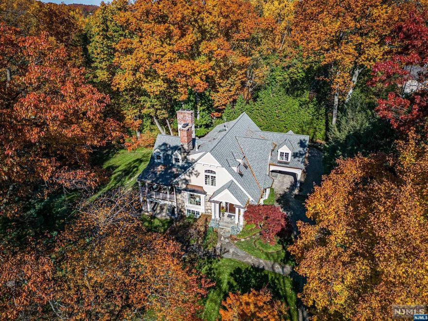 Total privacy awaits at this welcoming and sophisticated custom-built, 20-year young expansive colonial nestled on a picturesque half acre at the end of a cul-de-sac. The stunning exterior facade consists of natural stone, stucco, gorgeous chimneys, copper gutters, a deck and two covered front porches that connect the home to all aspects of surrounding nature. The heart of the home consists of a great room with 18-foot ceilings attached to the gourmet kitchen with an eat-in nook. A grand living room with fireplace, dining room, mudroom, and laundry rounds out the first floor. The primary suite features a vaulted ceiling, a large walk-in closet for two, and a spa-like bath. Walkout basement with gym, 2 large living spaces with fireplaces, and French doors onto the side hill. Notable features include Porte-cochere, 5 fireplaces, 3 car attached garage, hardwood floors, and first-floor bedroom/office. All this and a prime location in the coveted Old Country Club section of Ridgewood!