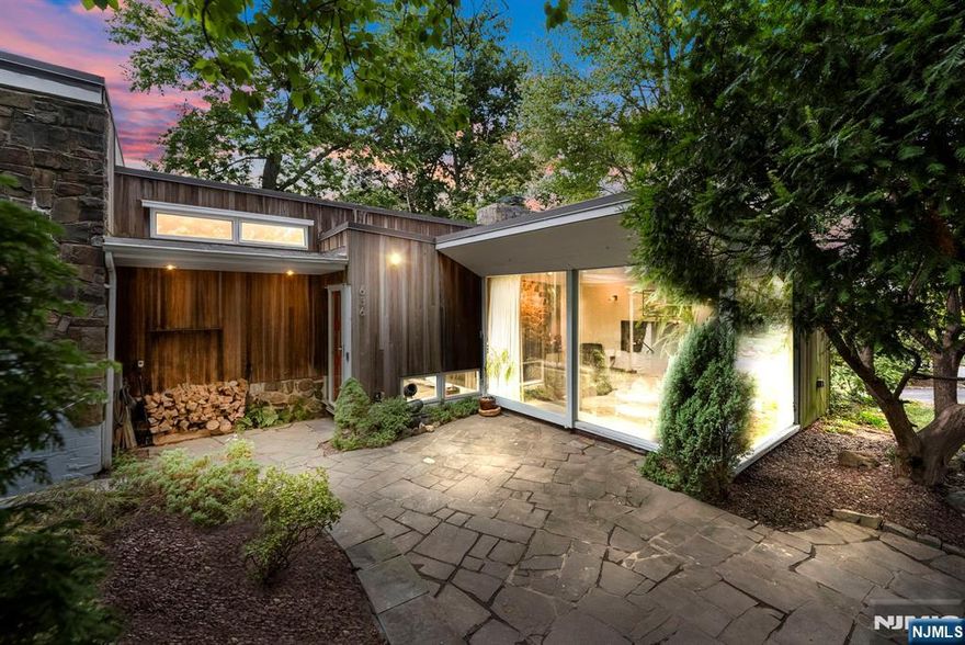 Nestled on the border of Englewood/Fort Lee sits this mid century modern architectural masterpiece. You are immediately greeted by the manicured landscaping, pond, stone walkways and abundant trees. As you walk in to the first level you will find the renovated kitchen with quartz countertops & center island, stainless steel appliances and sleek soft close cabinets. The open concept flow leads to a spacious dining area, with access to the outside terrace with a grill, sitting area and perfect for relaxation. The ground floor family is the perfect entertainers paradise with abundant space, oversized windows, and a stone wood burning fireplace. Upstairs you will find the 2 spacious bedrooms with the primary having a large oversized window perfect for the natural light lovers. The modern bathroom features a large walk down stand up tiled shower. The basement is fully finished and provides great flex space or as a in law suite with a full bathroom. The fully fenced in backyard provides great gardening area, a jacuzzi that can be used year round and enough recreating room to entertain. The home has been carefully renovated and crafted over the years adding updates such as radiant hydronic heating, a brand new paved driveway, tankless water heater, custom modern closets throughout and much more. Homes like this don't come around too often and this one will be sure to impress!