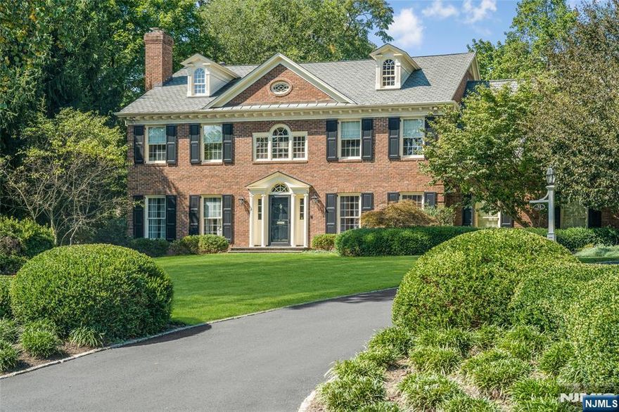 Set back from the street with a long tree-lined approach, this timeless Georgian brick Colonial makes an immediate impression with its symmetry, scale and quiet confidence. Ideally located in one of the most coveted in-town settings, the home offers rare proximity to the train and local schools -- an exceptional convenience that elevates everyday living. Mature trees, manicured hedges and lush lawns create a sense of arrival that feels both private and refined, while extensive millwork, custom built-ins and elevated finishes reflect consistent quality throughout. Built in 1989, this residence stands apart in a neighborhood known for much older homes, offering the comfort, layout and infrastructure of more modern construction while honoring classic architectural details. A columned portico opens to a gracious center hall, flanked by formal living and dining rooms. The rear of the home unfolds into an expansive family room, breakfast room and kitchen inspired by Clive Christian design. A first-floor library with full bath offers flexibility as a bedroom suite while upstairs each bedroom is thoughtfully positioned and paired with its own bath, including a spacious primary retreat with luxurious bath and custom walk-in closet. The finished lower level offers areas for media, office, exercise, wine storage and more. Outdoors, a bluestone patio overlooks a deep level lawn framed by mature landscaping -- private, serene and perfectly suited for entertaining or quiet moments at home.