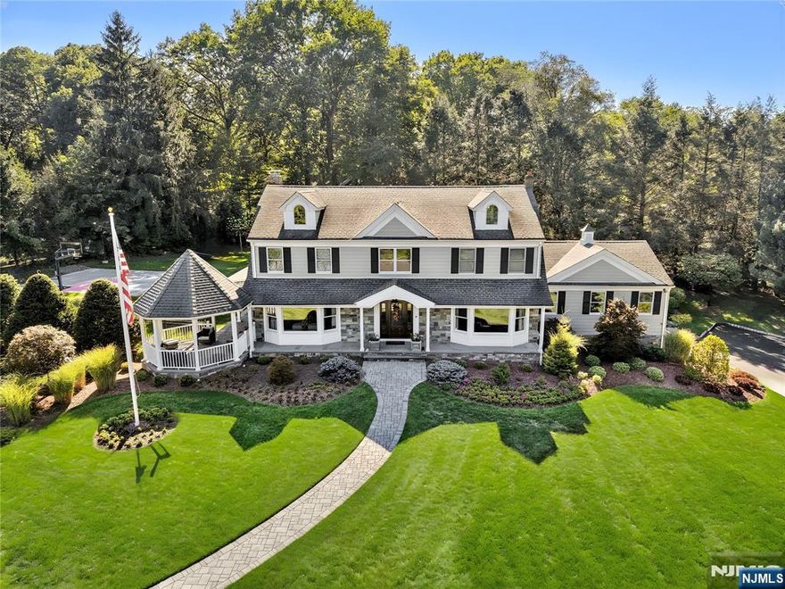 Pristine Center Hall Colonial, renovated from top-to-bottom in 2012, nestled on over an acre of picturesque grounds. This 5-bedroom, 3.5-bath home combines timeless curb-appeal and modern amenities, highlighted by a backyard that's perfect for entertaining, with expansive patios for outdoor dining, a vaulted-ceiling pavilion with a fireplace and built-in kitchen (2014), and a fenced yard with a basketball court. A wrap-around porch greets you to the bright 1st level with hardwood floors and quality millwork throughout, starting with a foyer flanked by a living room and formal dining room with coffered ceiling and wet bar. At the heart of the home is a gourmet eat-in kitchen, equipped with high-end appliances, marble countertops, and an oversized center island that opens to a family room with fireplace. A convenient 1st floor ensuite bedroom or home office, laundry room, and powder room complete the level. Upstairs, the primary suite impresses with a vaulted ceiling, large walk-in closet, and a spa-like bathroom. The finished basement offers plenty of recreation/living space, a gym, and mudroom access to the 2-car attached garage. Other highlights: radiant heated flooring in bathrooms, smart security & landscaping features, indoor/outdoor sound system, energy efficient features, and in a prime commuter town near Ho-Ho-Kus' NYC-bound train. Truly an exceptional property!