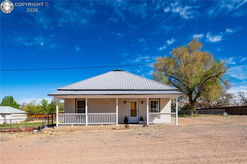 Farmhouse inspired home with a porch, a metal roof, and stucco siding