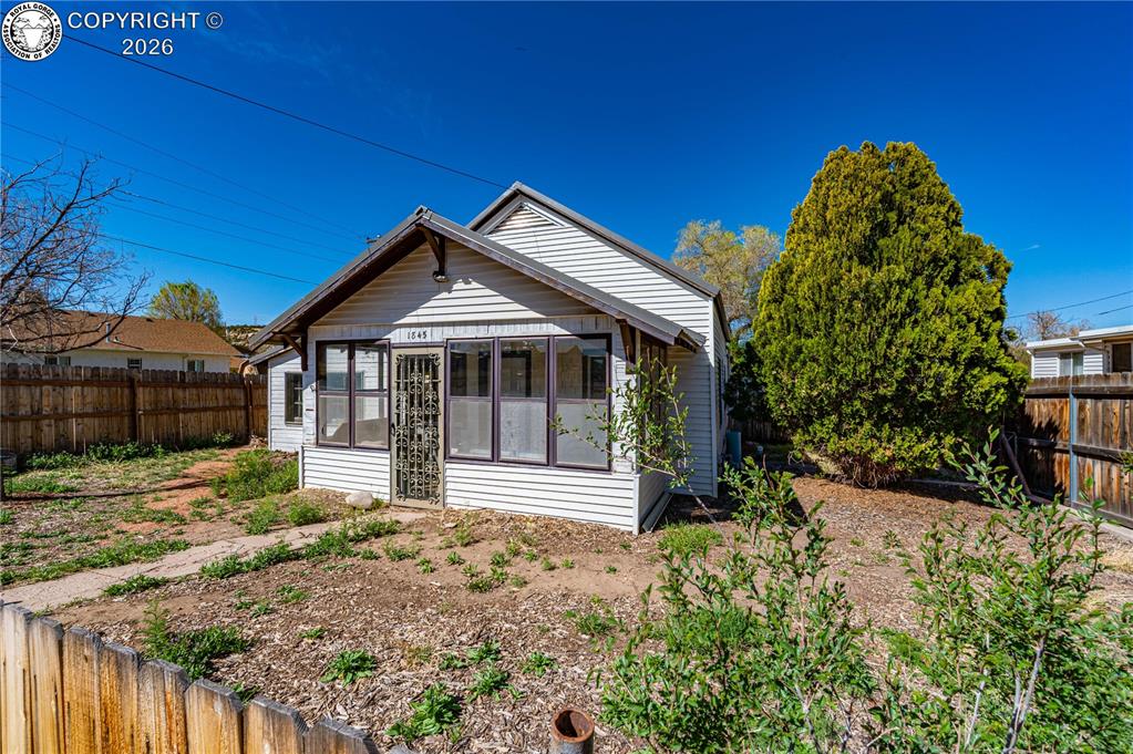 Rear view of property with a fenced backyard and a sunroom