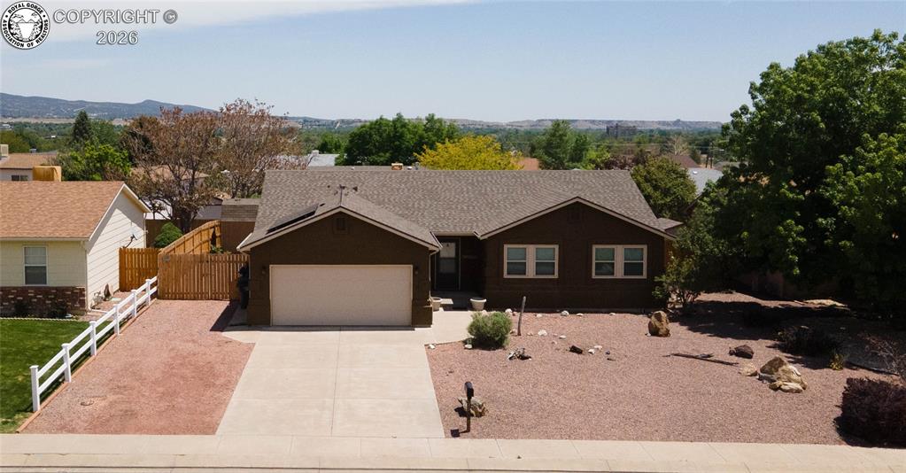 Single-story residence featuring a dark brown exterior siding, attached two-car garage, and a low-maintenance xeriscape front yard with decorative rocks