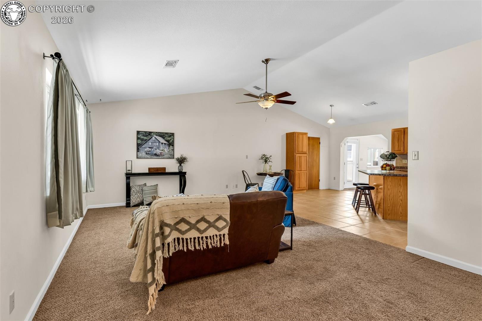 Bedroom with light carpet, baseboards, lofted ceiling, light tile patterned floors, and a ceiling fan