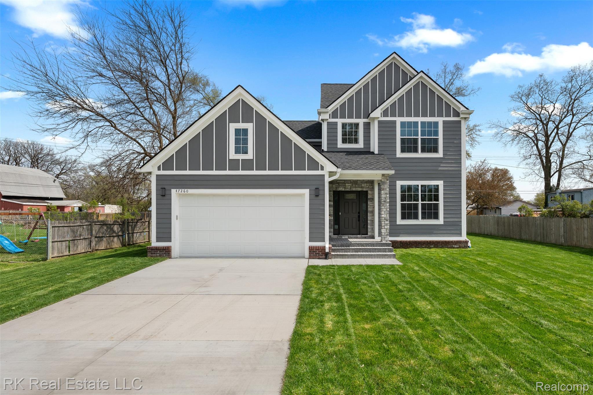View of front facade with board and batten siding, driveway, and a shingled roof