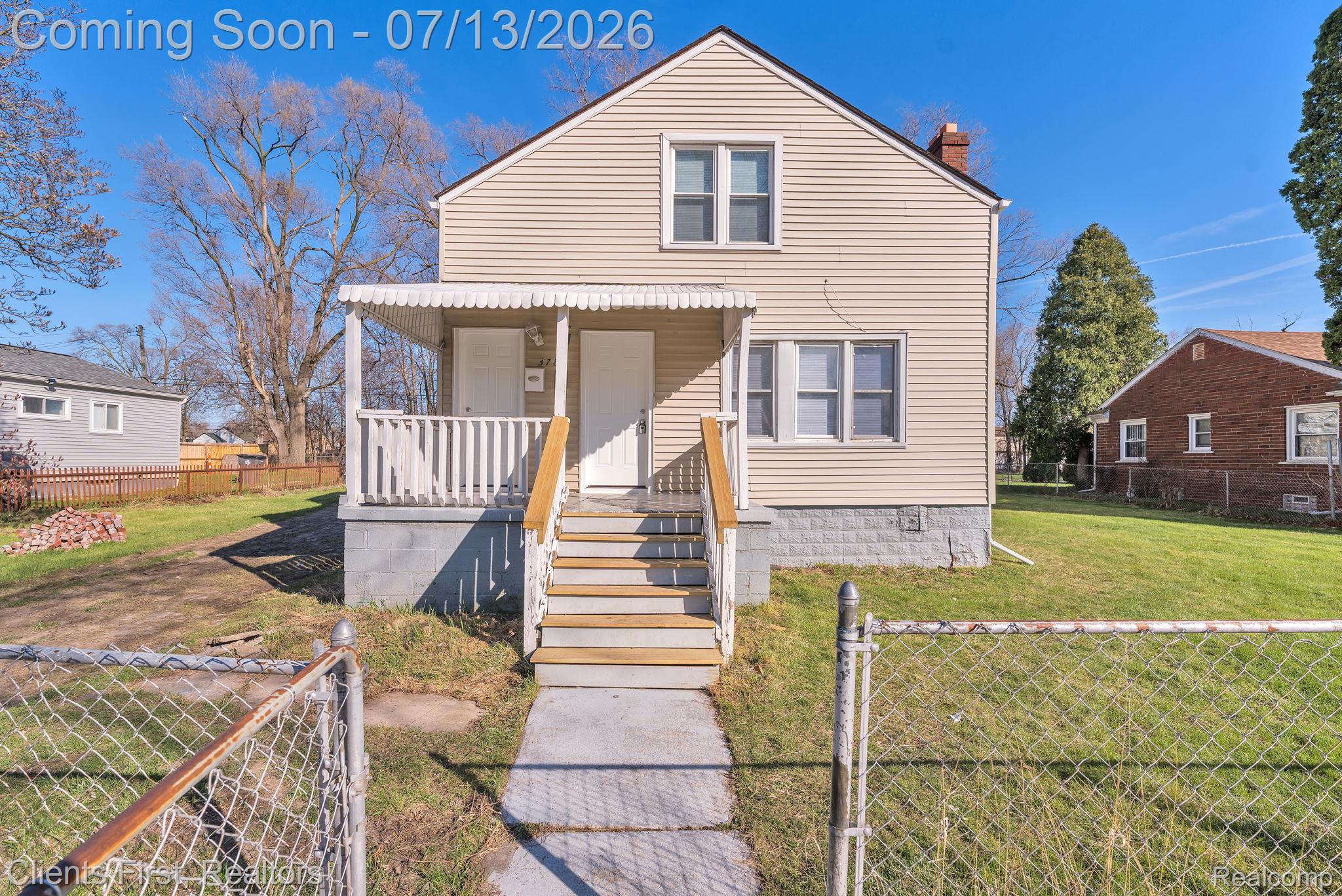 Two-story home with light-colored siding, a covered front porch, and a concrete walkway