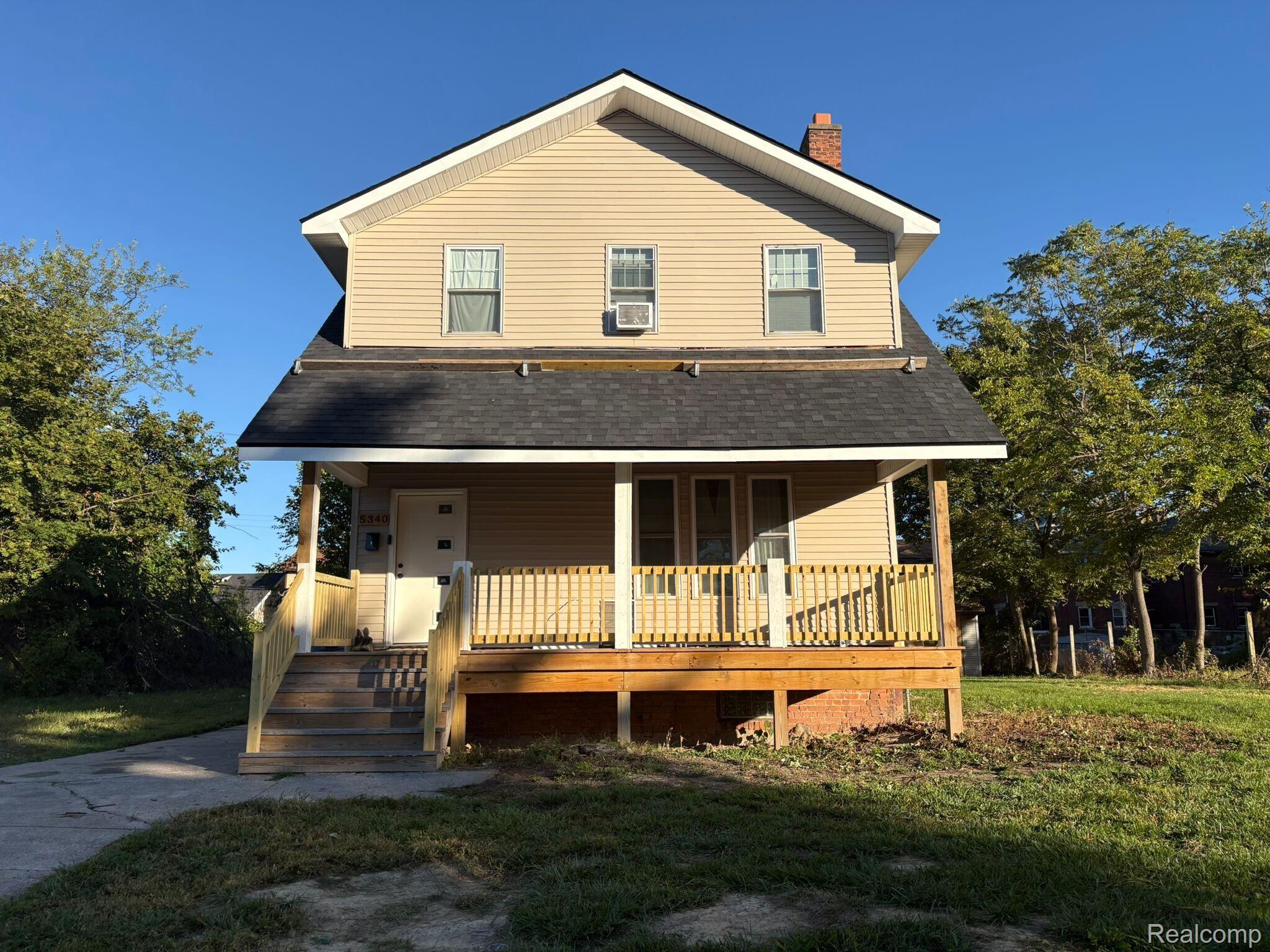 View of front facade featuring a porch, a chimney, roof with shingles, and a front lawn